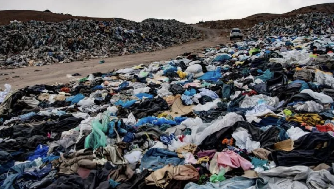 A vast landfill overflowing with discarded clothing, illustrating textile waste issues