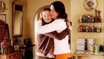 Rory and Lorelai Gilmore from the show The Gilmore Girls embracing in their kitchen