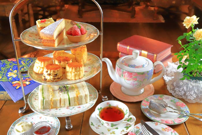 アフタヌーンティーセットがテーブルに並べられている。サンドイッチ、スコーン、ケーキが含まれる。