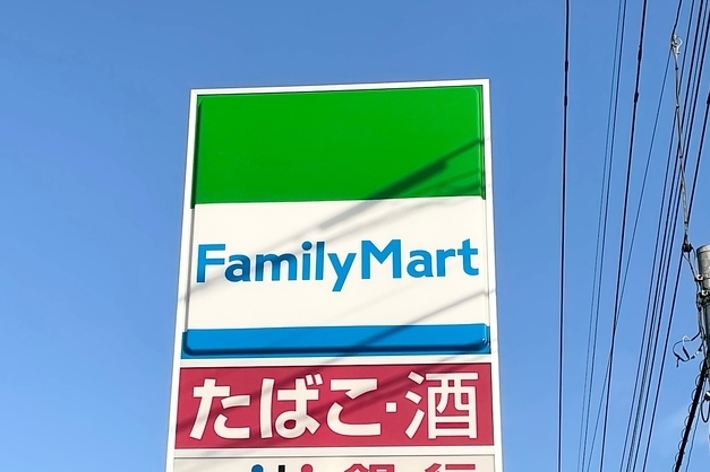 ファミリーマートの看板、青空の背景、トイレおよびATM利用可能サービスの表示。