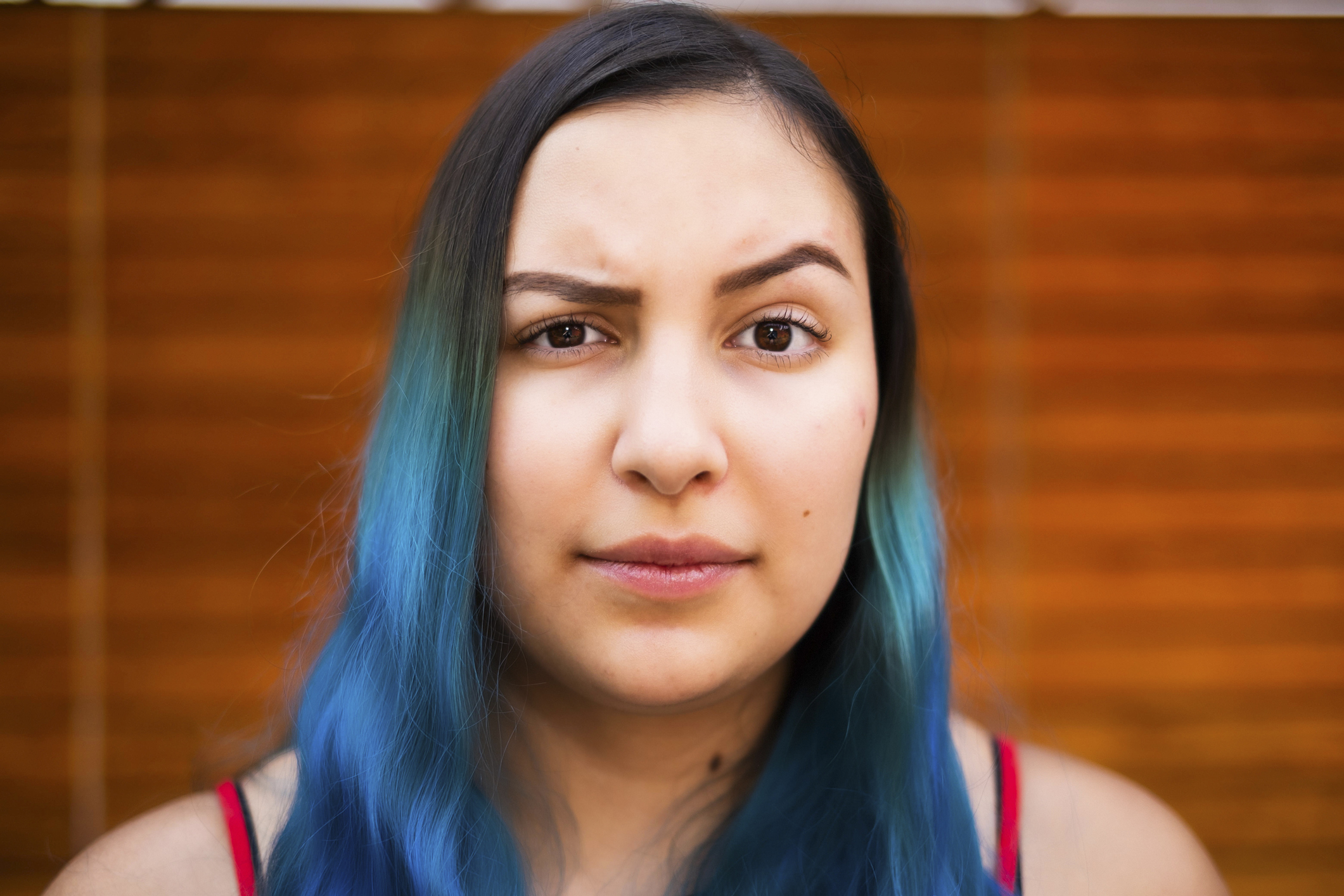 Woman with blue hair looking directly at the camera with a neutral expression