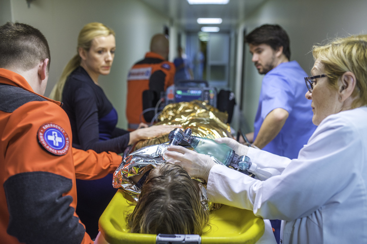 Medical team rushing a patient on a stretcher through a hospital corridor