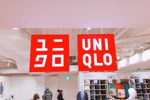 ユニクロの店内で、赤い看板に白字で「ユニクロ」と「ユニ」のロゴ、衣類を見ている人々とマネキンがある。