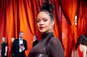 Rihanna stands on the red carpet in a chic, sheer black gown with a high neckline