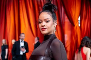 Rihanna stands on the red carpet in a chic, sheer black gown with a high neckline