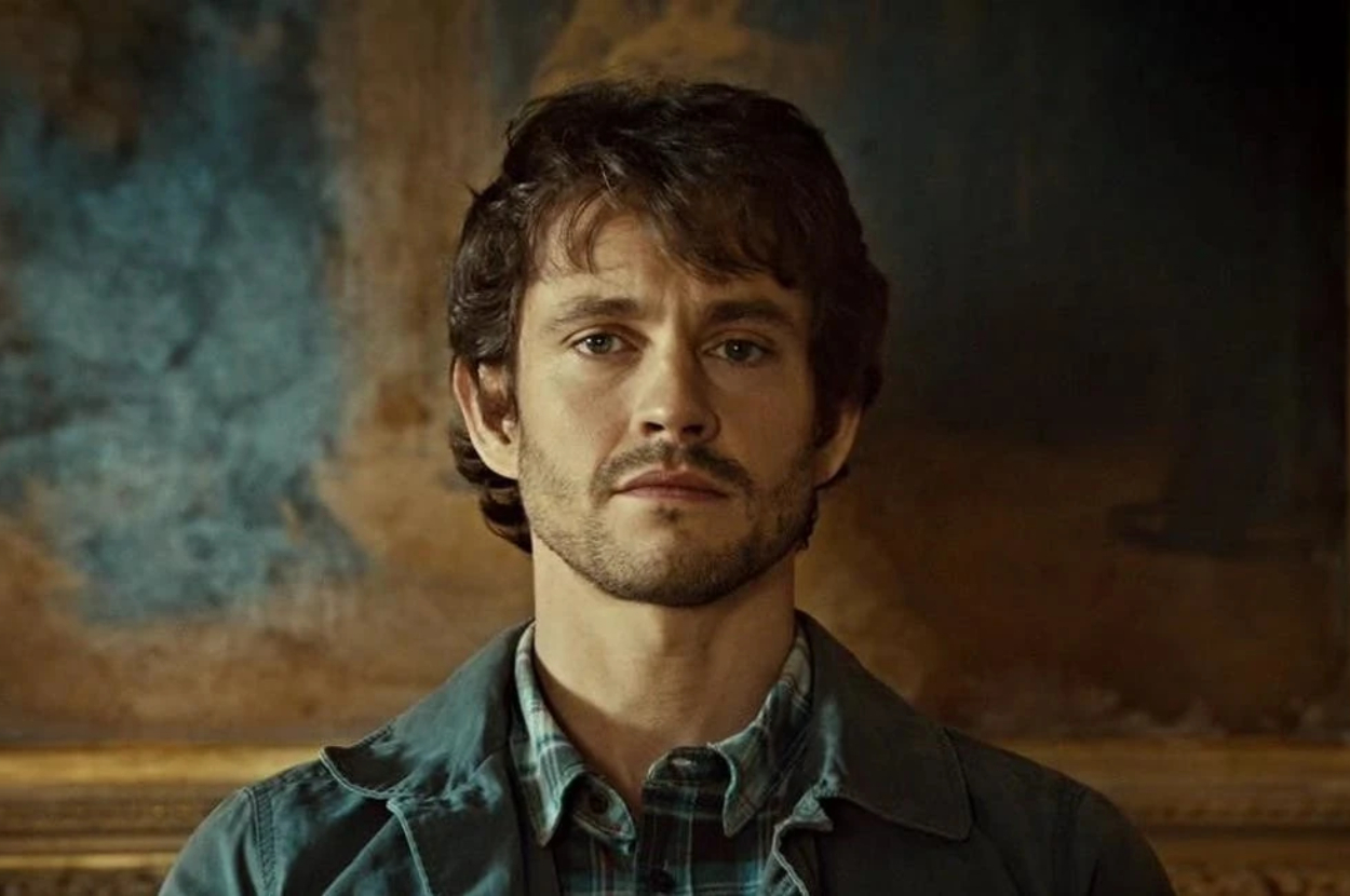 Hugh Dancy as Will Graham in a plaid shirt, looking pensive in front of a painting
