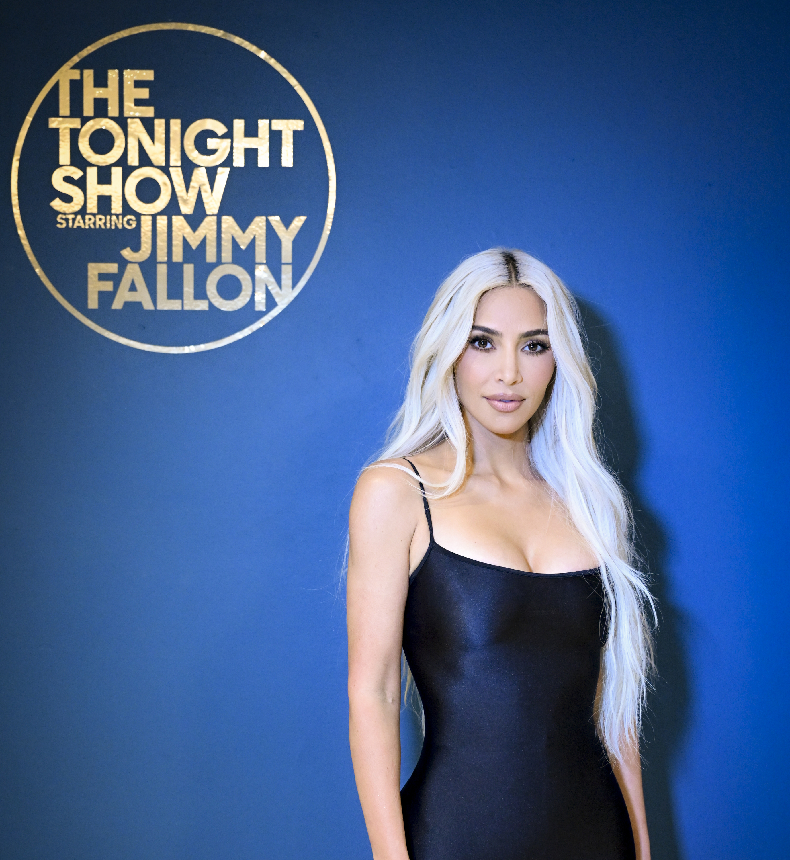 Kim Kardashian in a spaghetti0strap dress, standing before &quot;The Tonight Show Starring Jimmy Fallon&quot; sign