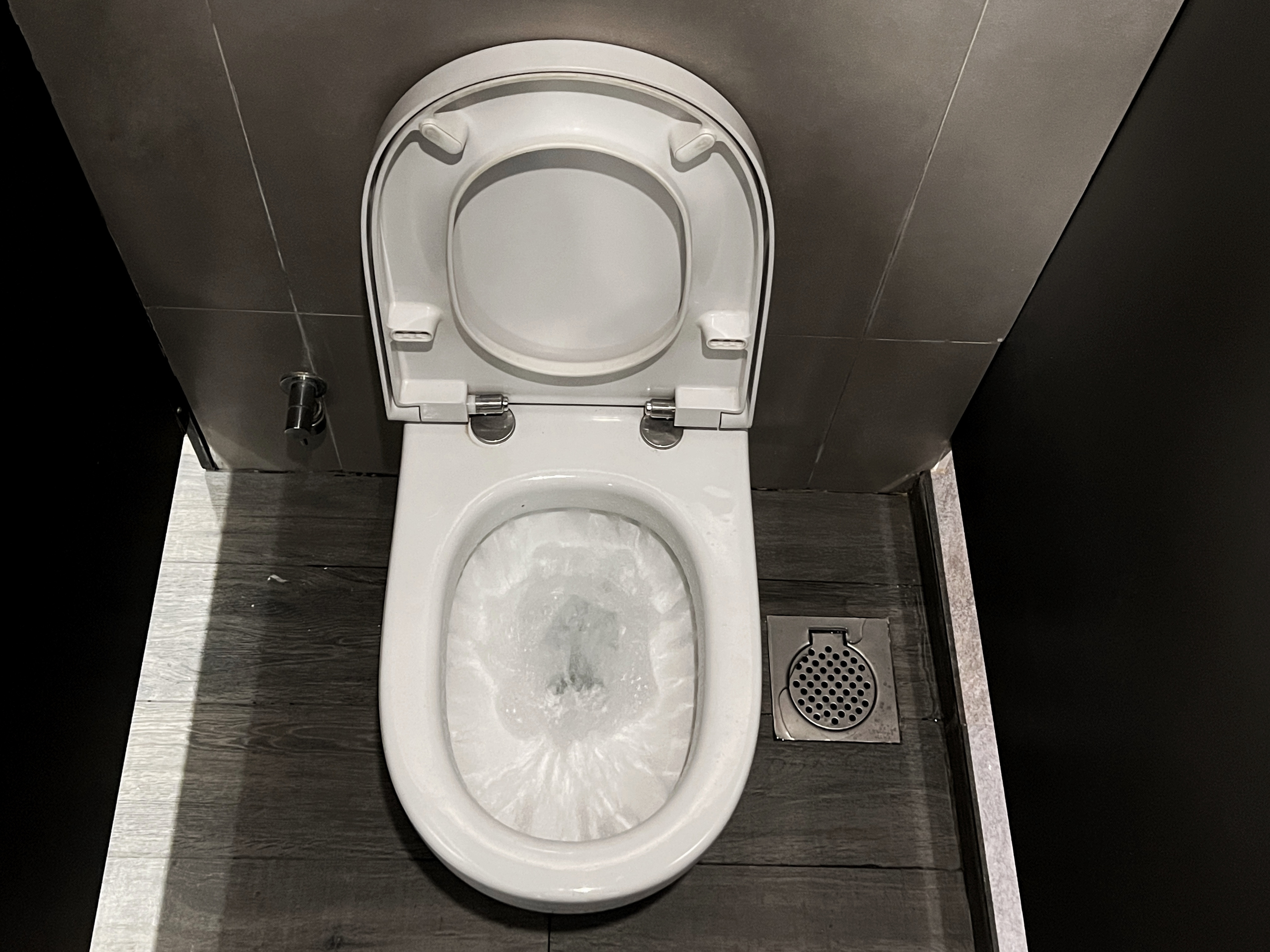 An open toilet with a seat cover in a restroom stall, no people visible