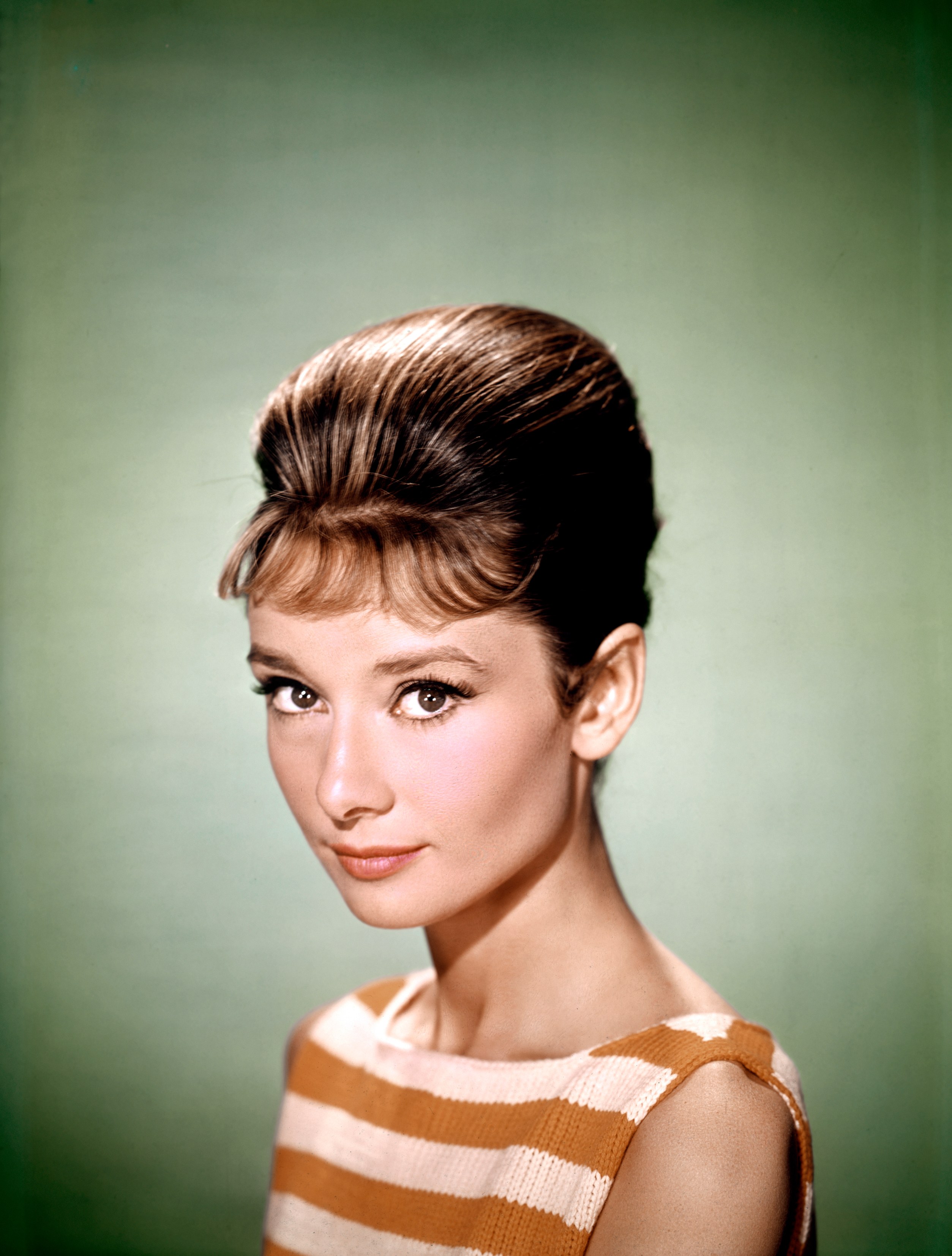 Audrey Hepburn in a sleeveless striped dress with an elegant updo hairstyle