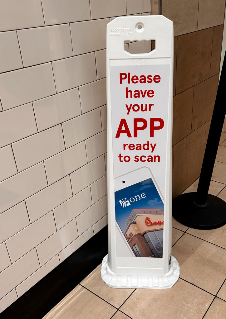 Sign instructing to have mobile app ready for scanning, with a phone displayed showing the app