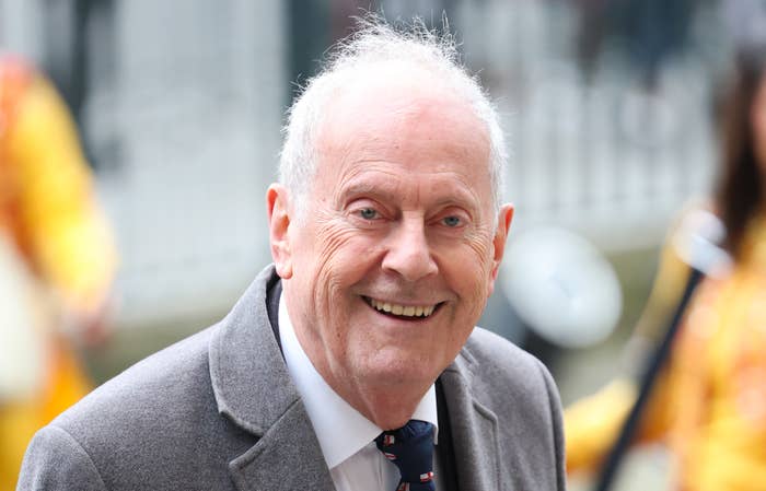 A closeup Gyles Brandreth of smiling while walking outside
