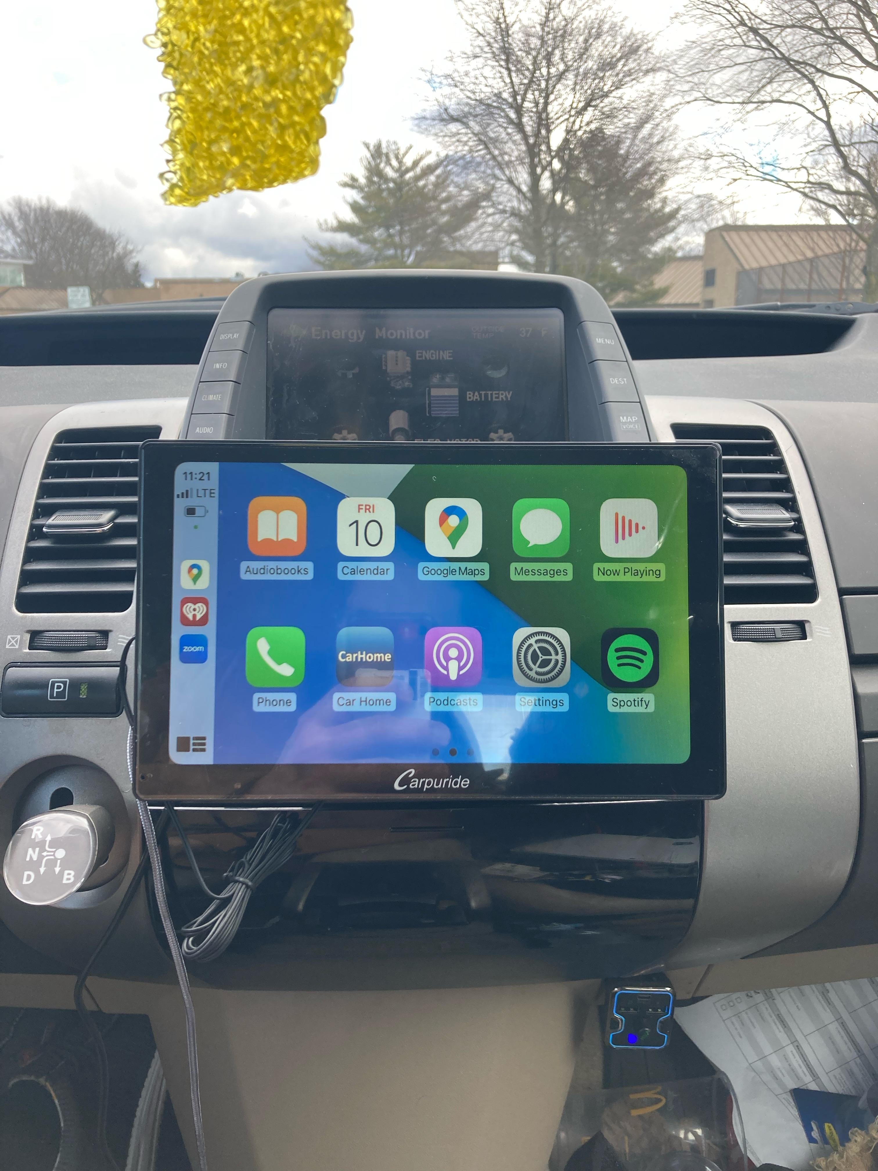 Tablet mounted on car dashboard displaying various app icons for navigation and media