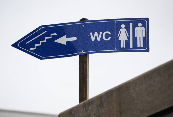 Sign indicating direction to WC with male and female symbols and an arrow pointing left
