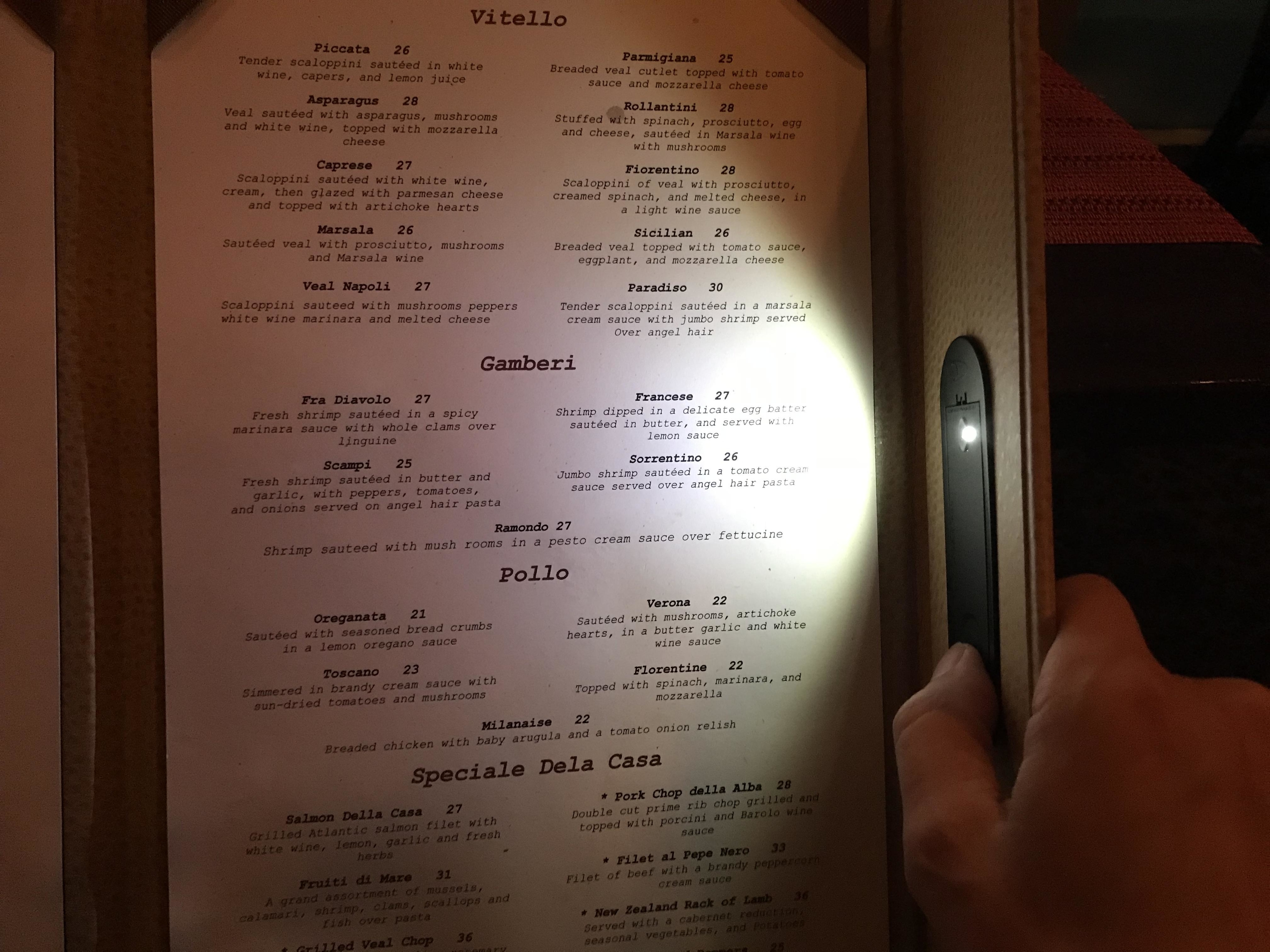 Menu with various Italian dishes in categories like Pizza, Vitello, and Speciale Dela Casa, person pointing at an item