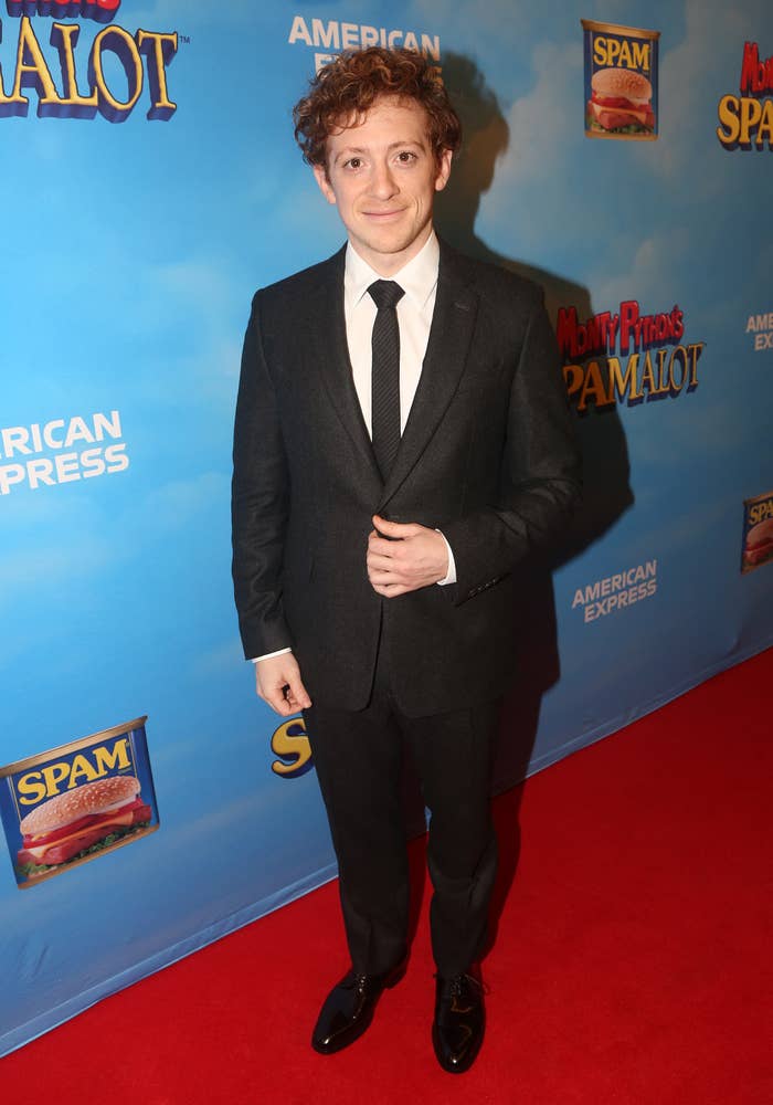 Ethan in a dark suit with tie smiling at a Monty Python&#x27;s Spamalot event