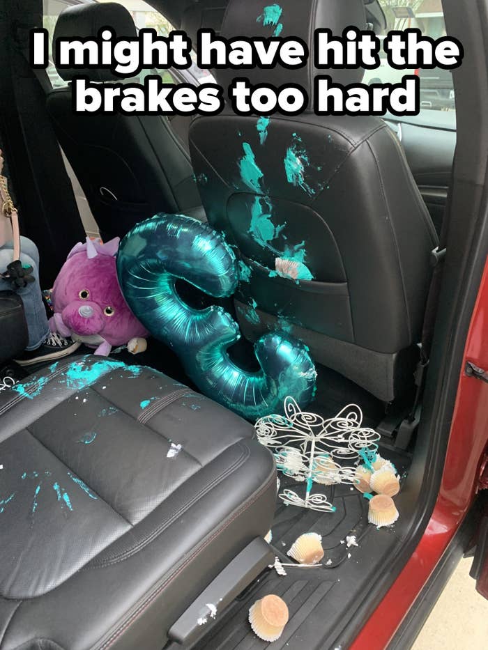 Backseat of a car with spilled party supplies, including a turquoise number 6 balloon, and a purple plush toy