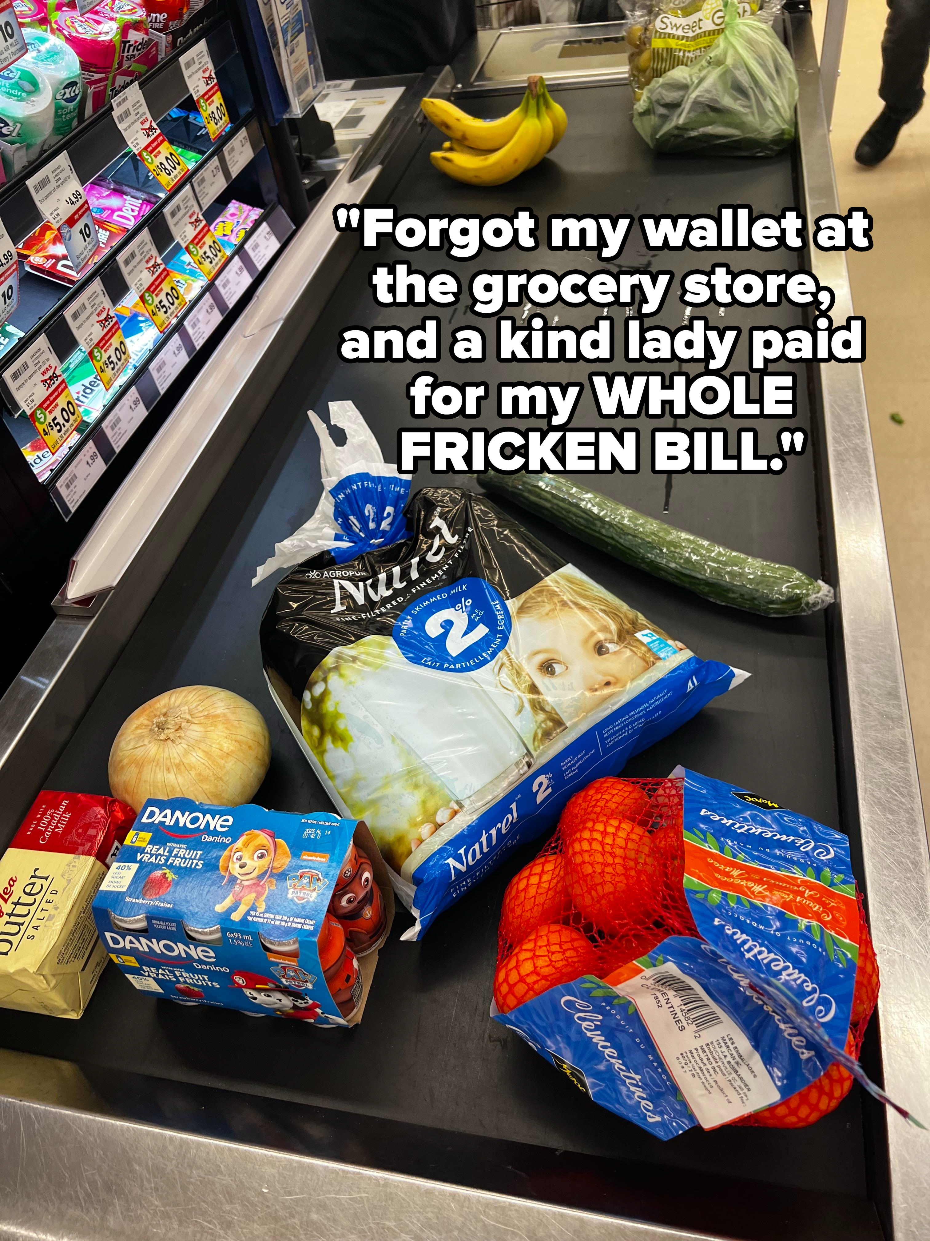 Groceries on a checkout conveyor belt, including fruit, vegetables, yogurt, and a magazine