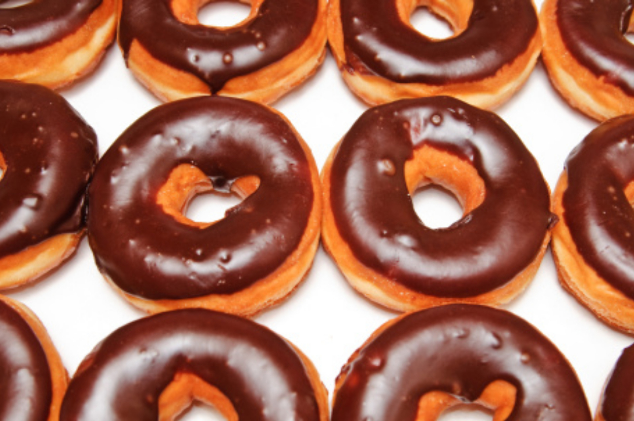 Chocolate glazed donuts arranged on a white surface
