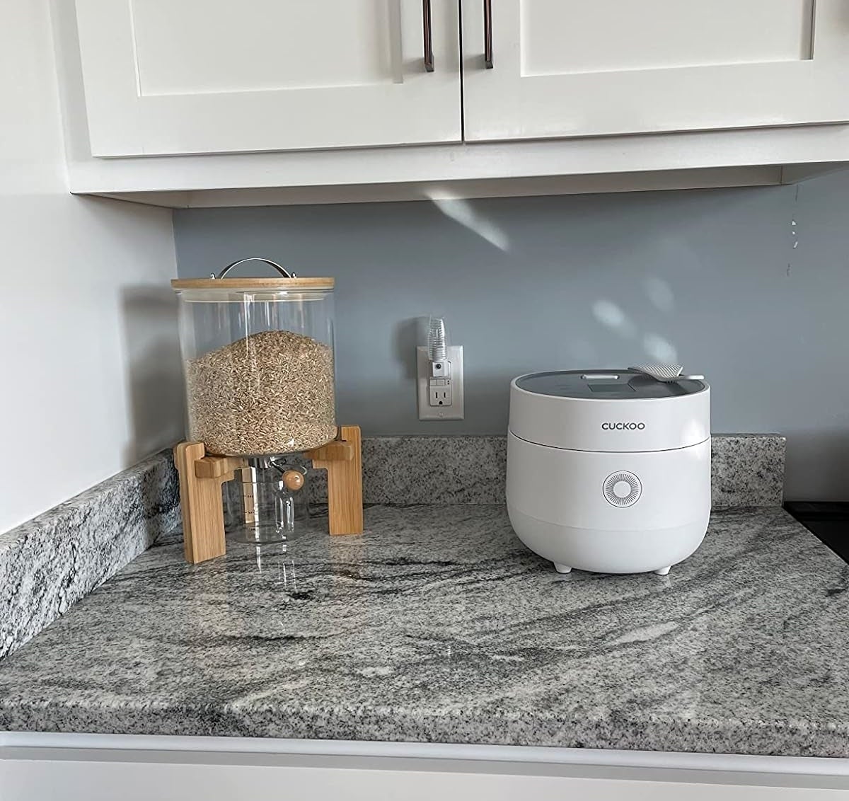 A rice dispenser and a Cuckoo rice cooker on a kitchen counter for efficient food prep
