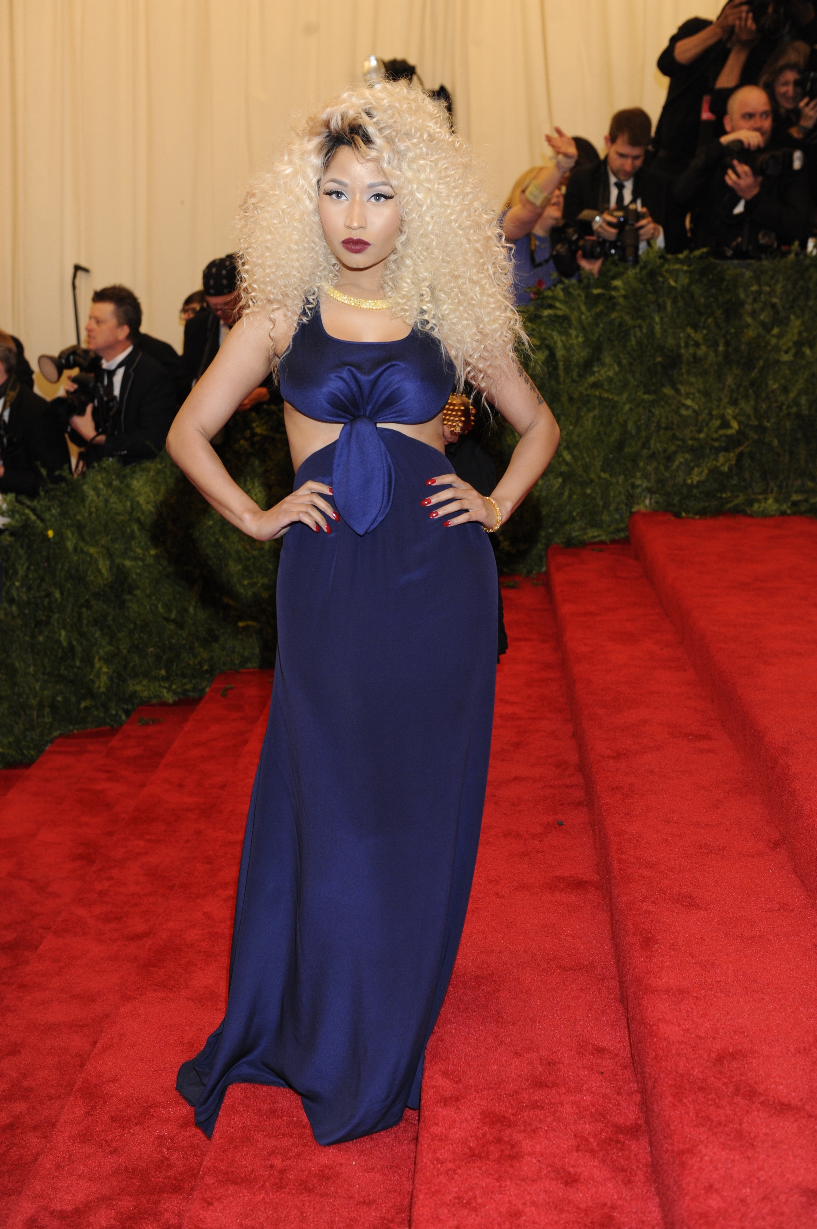 Nicki Minaj in an elegant blue dress with cut-out detail, hands on hips, at a red carpet event