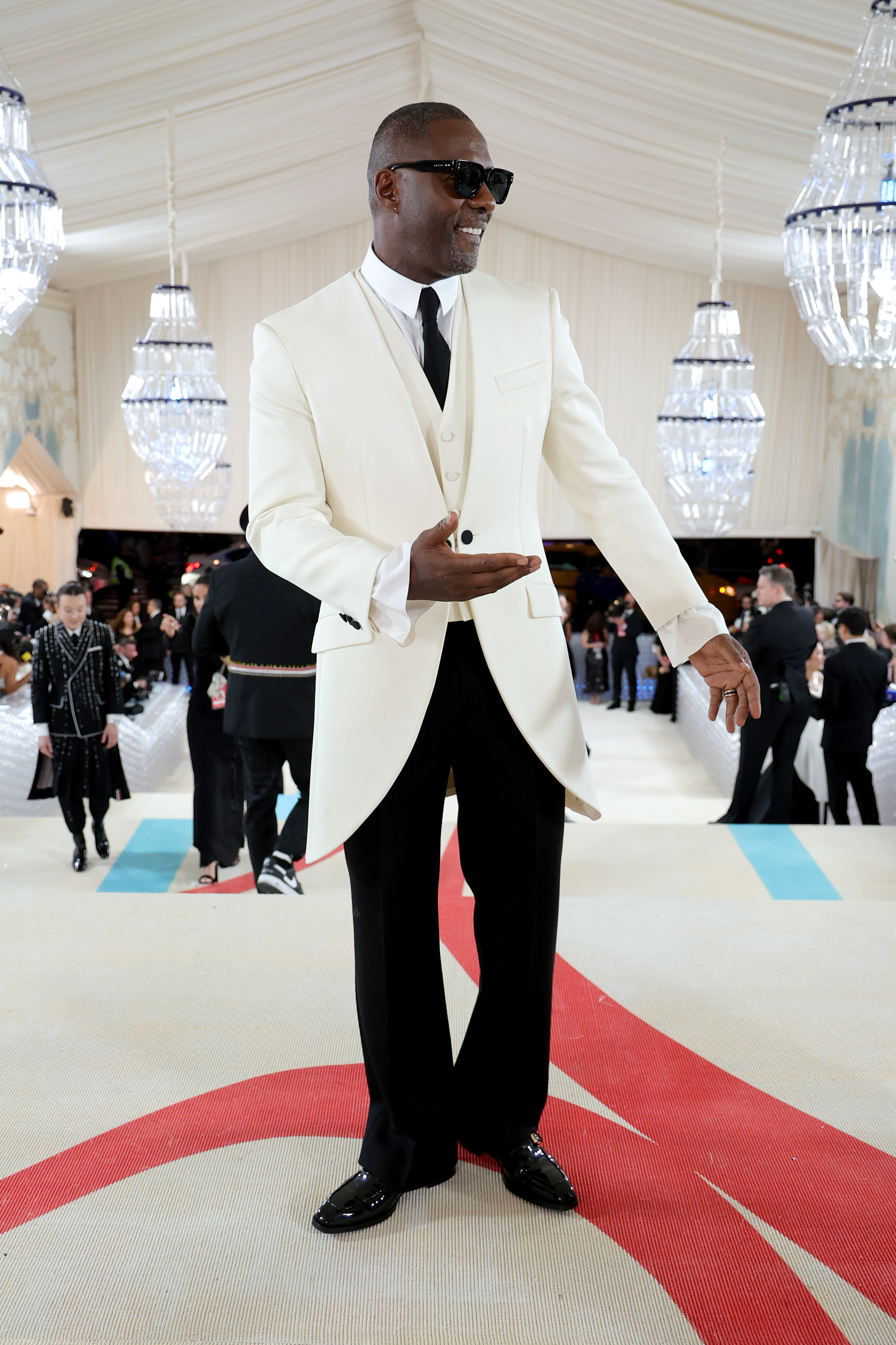 Man in a white tuxedo with black lapels and sunglasses on a gala event carpet