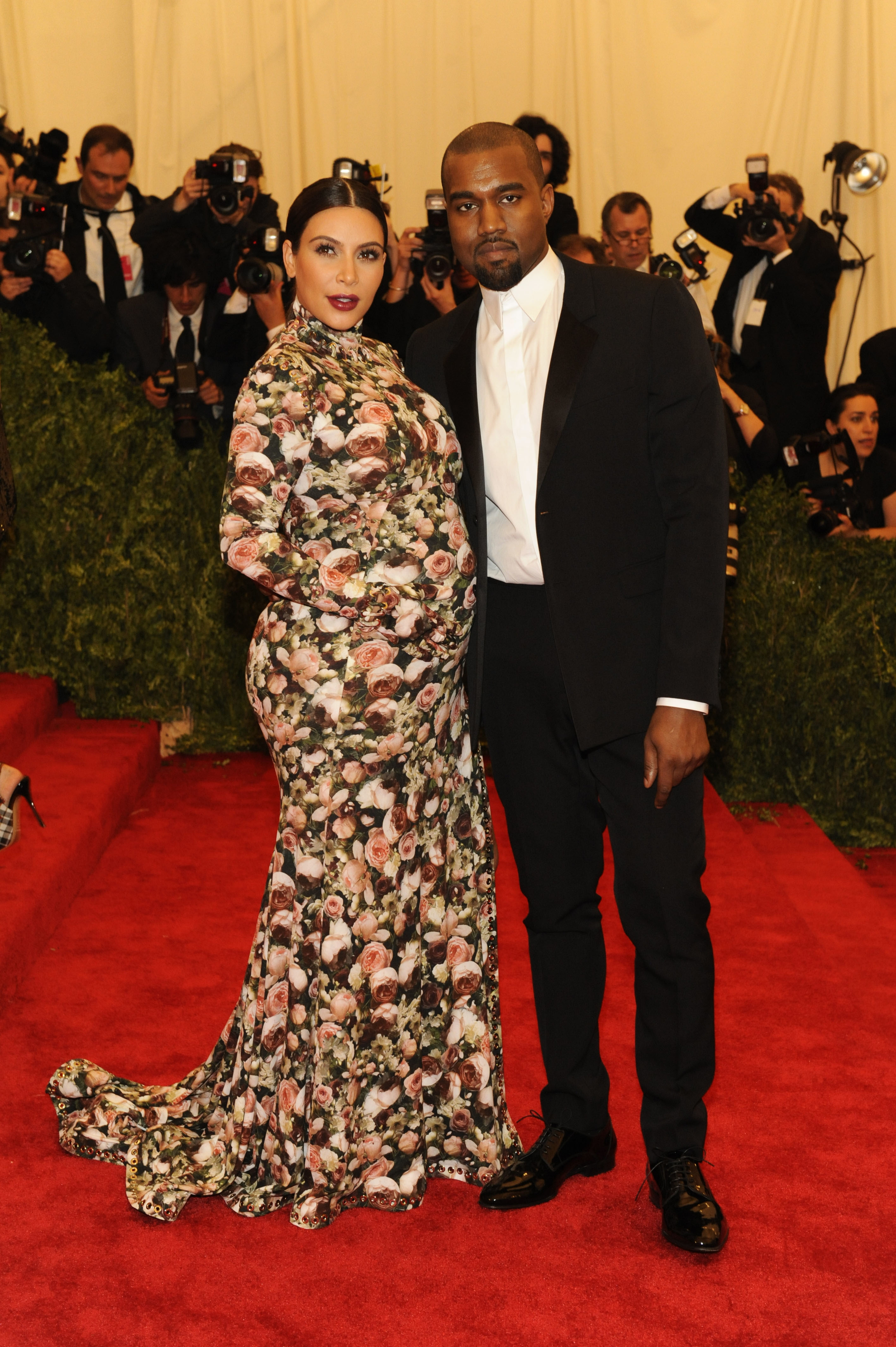 Kim Kardashian in a floral dress and Kanye West in a black suit on the red carpet