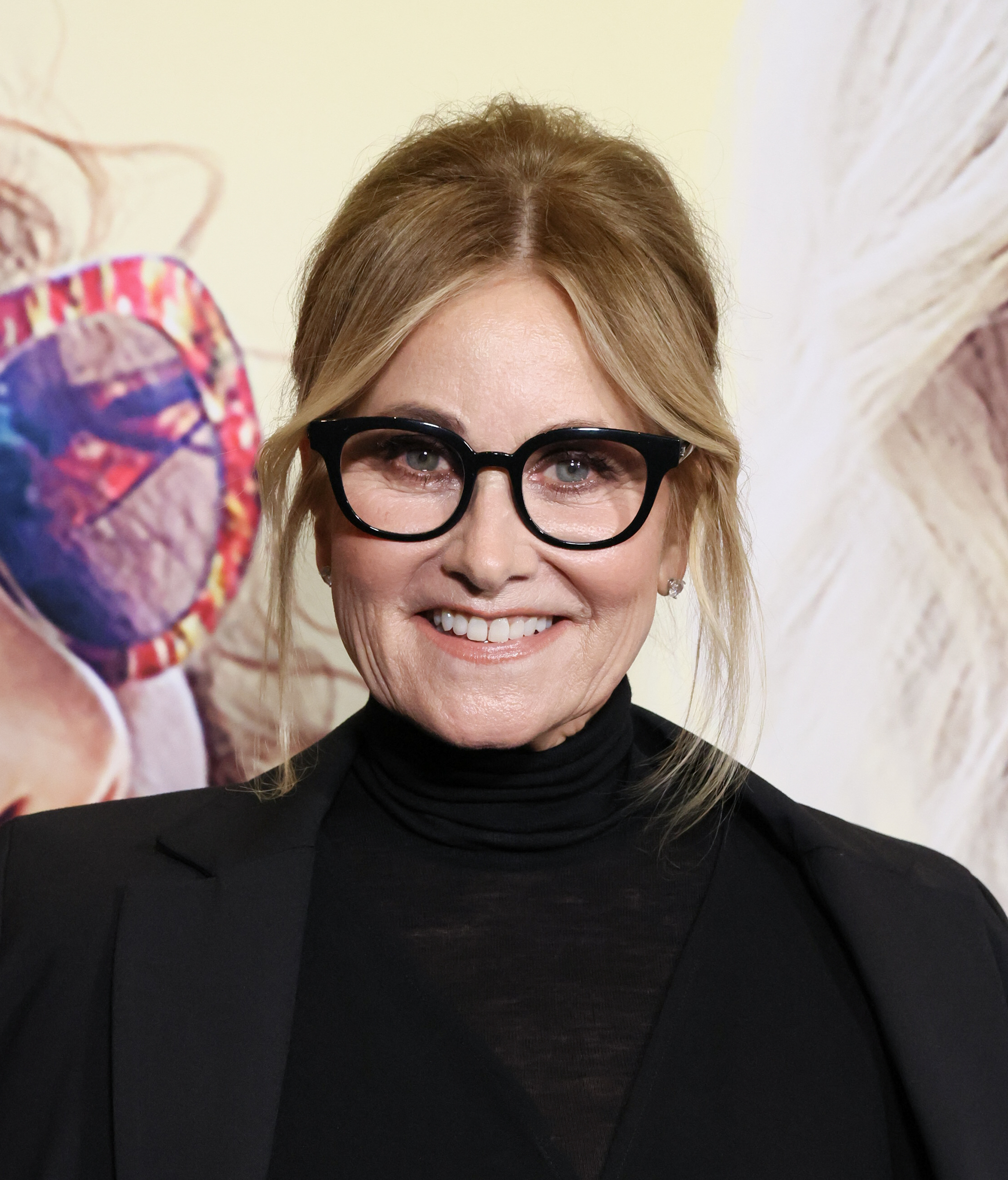 Woman with black glasses and black outfit smiling at an event