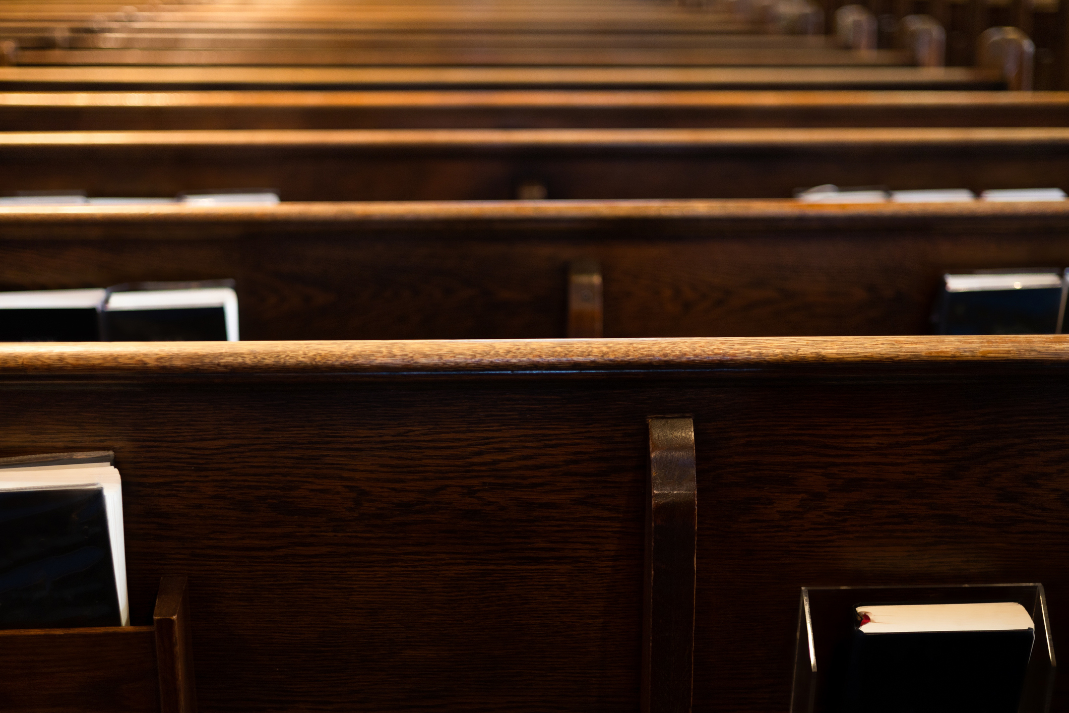 Row of empty church pews with hymnals, possibly for a family gathering or event