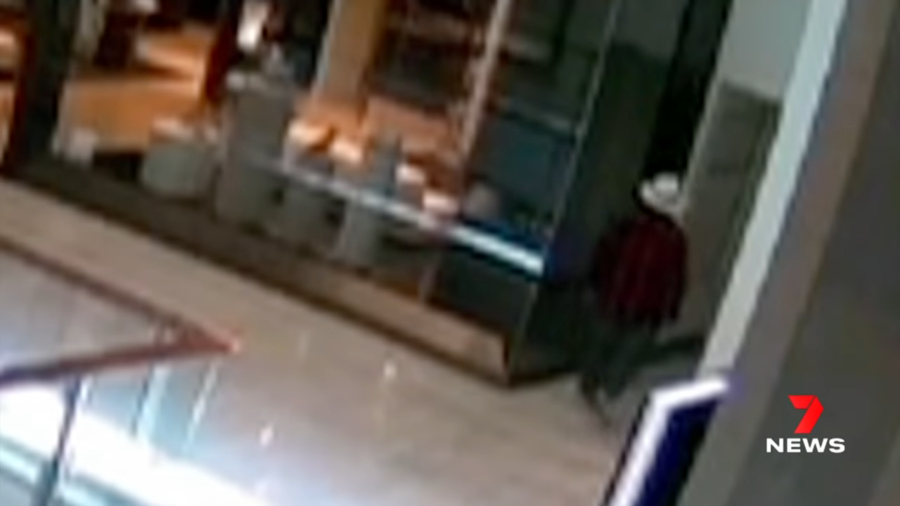 Surveillance footage of a blurry figure passing by a store after hours