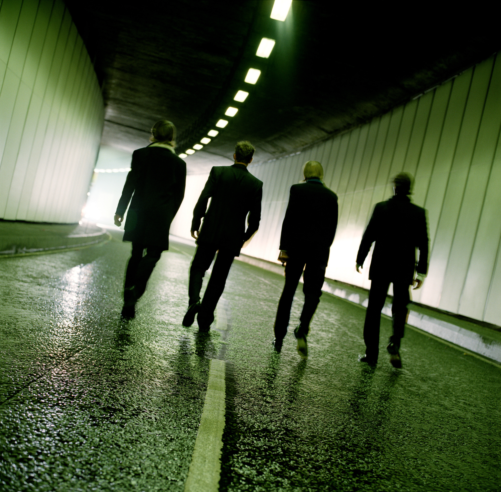 Four individuals walking away in a tunnel, possibly representing a metaphor for parental guidance or protection