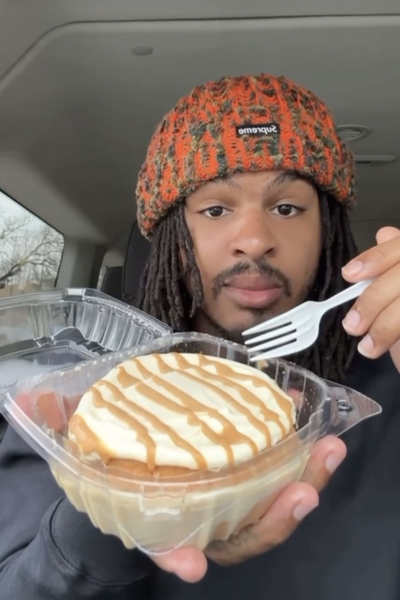 Keith Lee in car holds up a dessert in a plastic container, preparing to eat with a fork