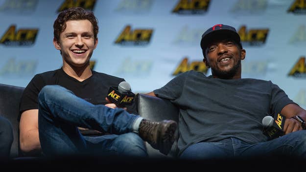 Tom Holland and Anthony Mackie sitting, laughing, holding microphones at a panel event