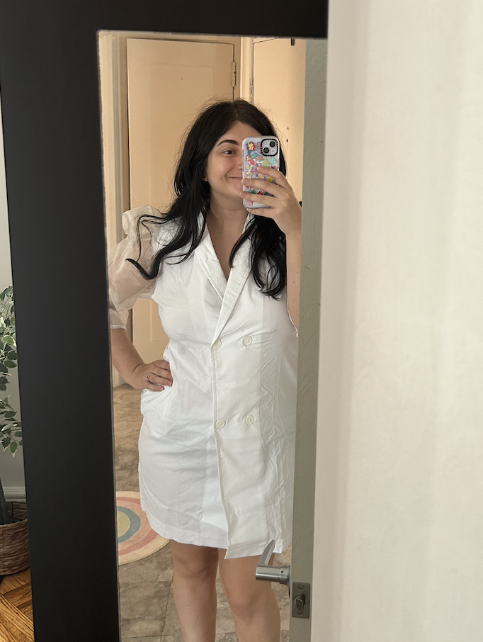 Person in a white dress takes a mirror selfie, phone covering face