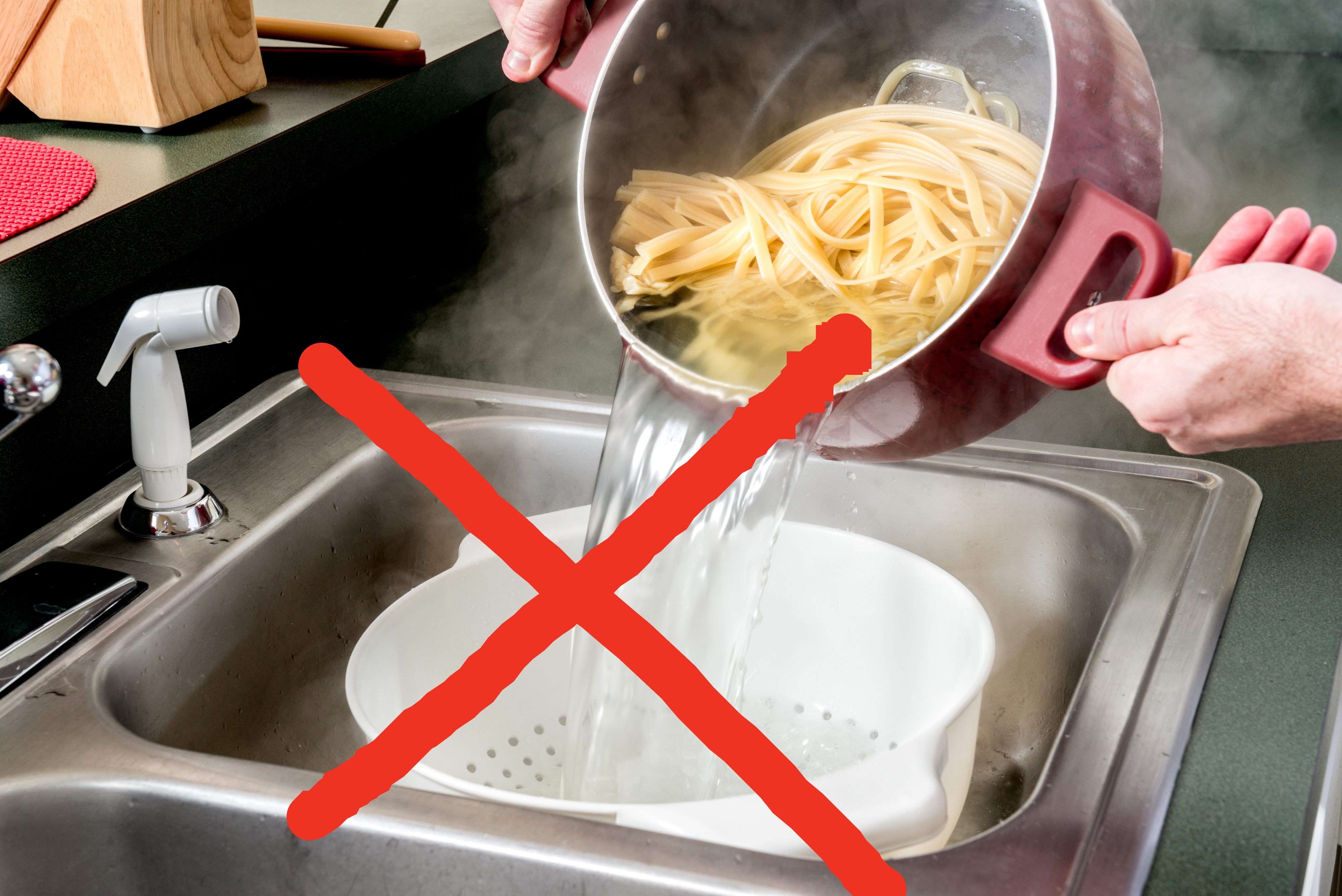 Person draining cooked pasta into a colander over a sink