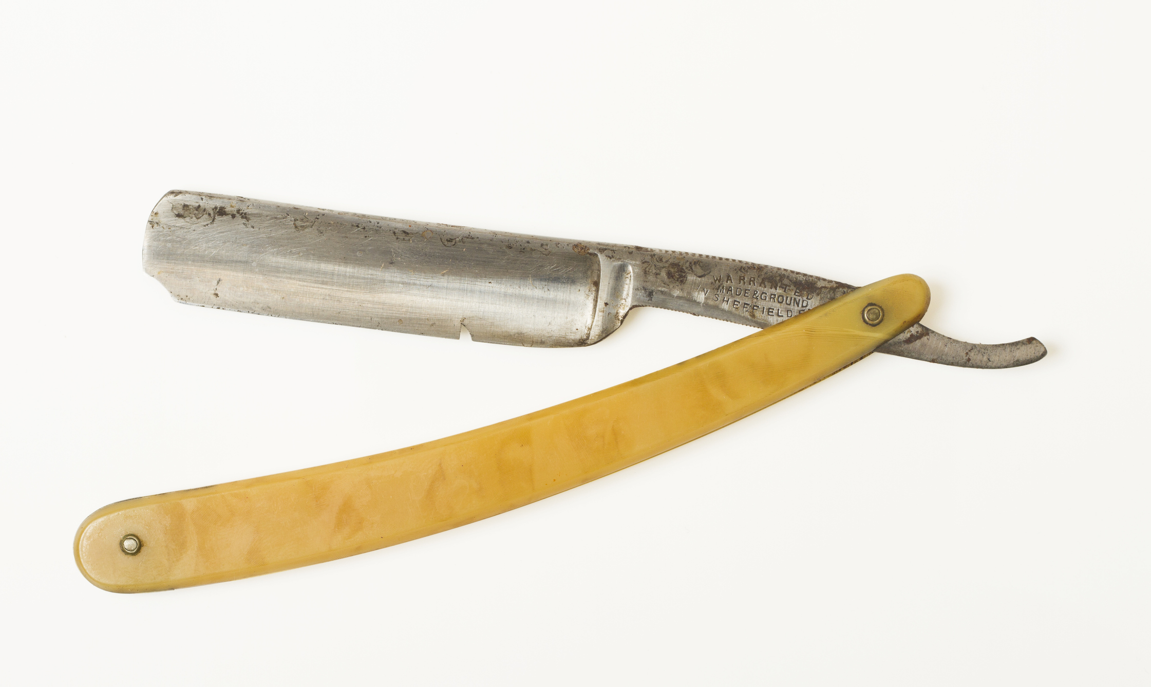 Vintage straight razor with ivory-colored handle on a plain background