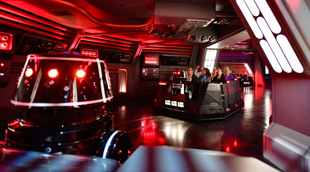 &quot;Visitors experience a space-themed attraction with futuristic control panels and a droid.&quot;