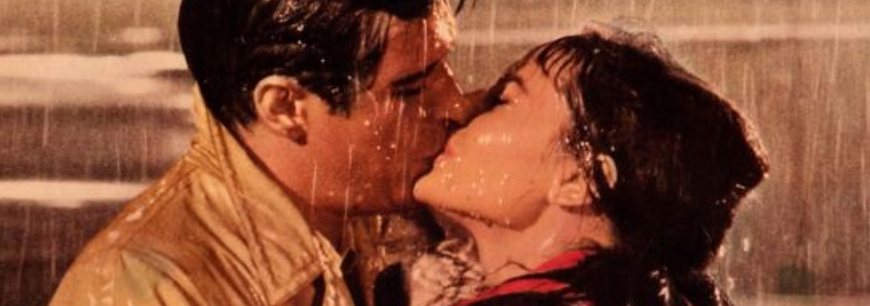 Two characters embracing and sharing a kiss in the rain from the film "Breakfast at Tiffany's."