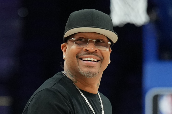 Man smiling wearing black hat, shirt, and sunglasses