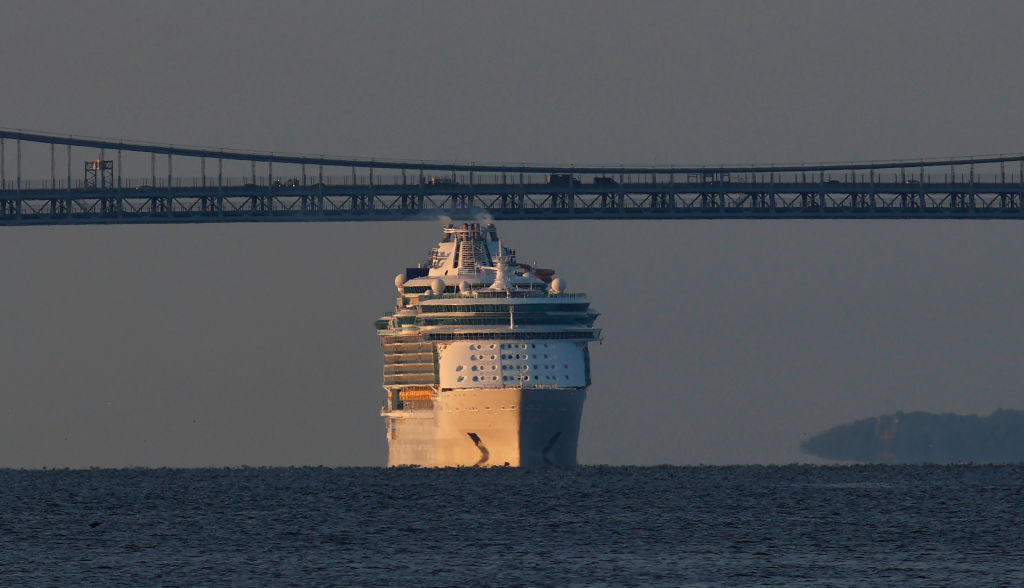 A cruise ship appears to be almost the same size as a distant bridge above it