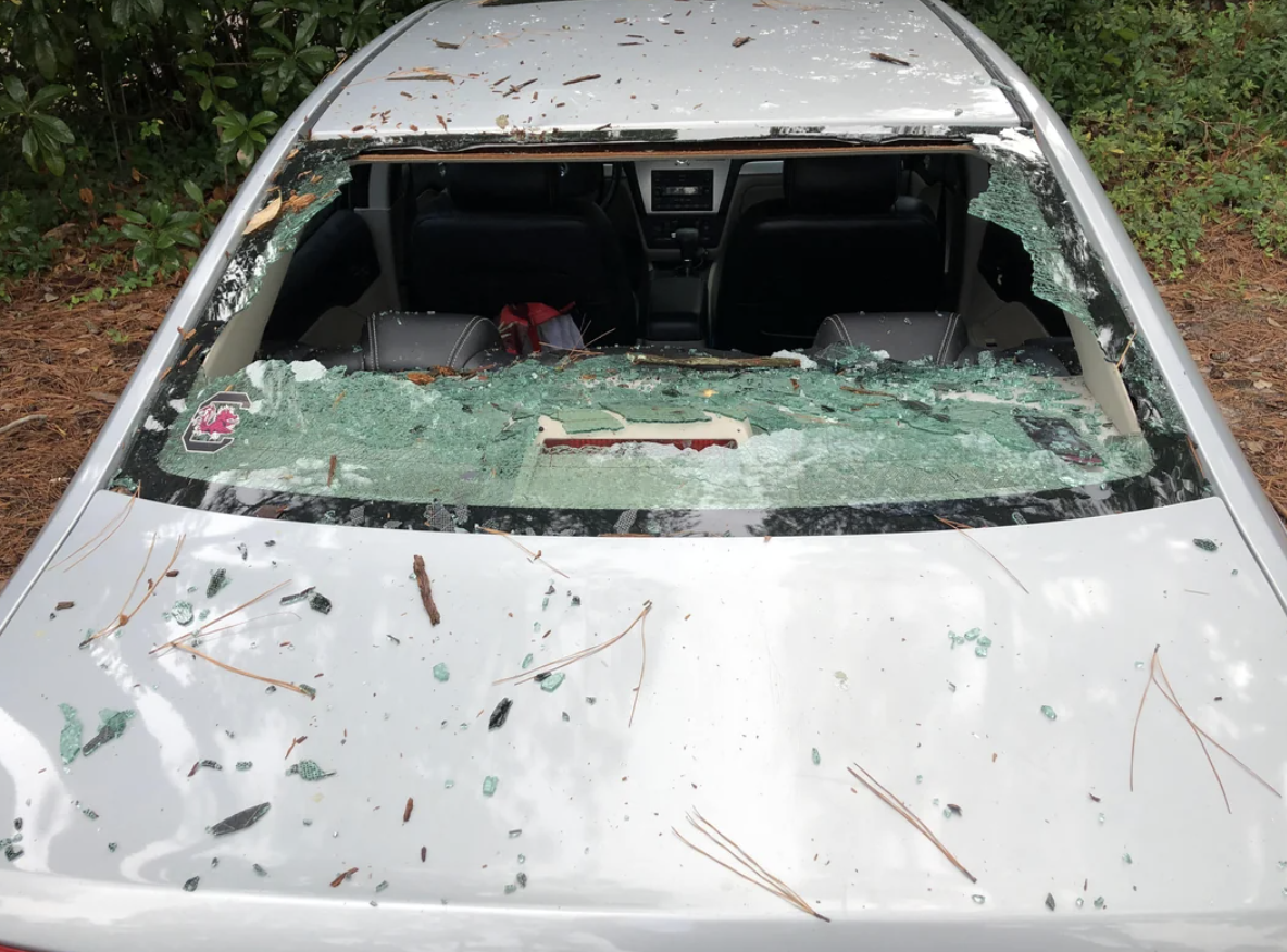 A car with a shattered windshield and debris scattered over the hood