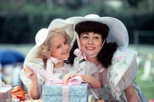 Mother and daughter in matching white dresses and hats with gift boxes