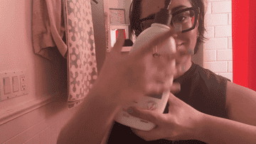 Person in a bathroom dispensing product from a bottle into their hand