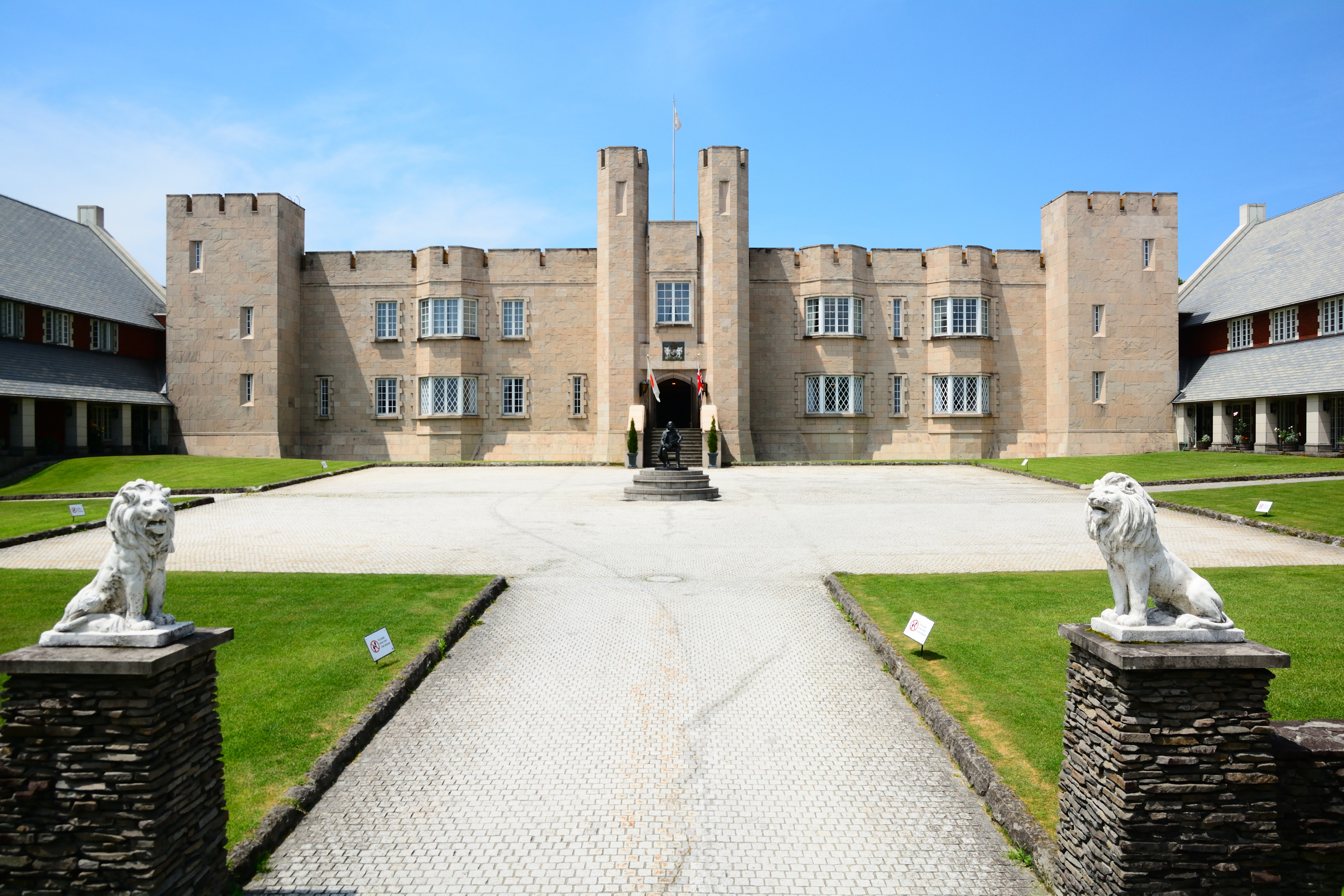 城の前の石畳の道とライオンの彫刻がある入口。