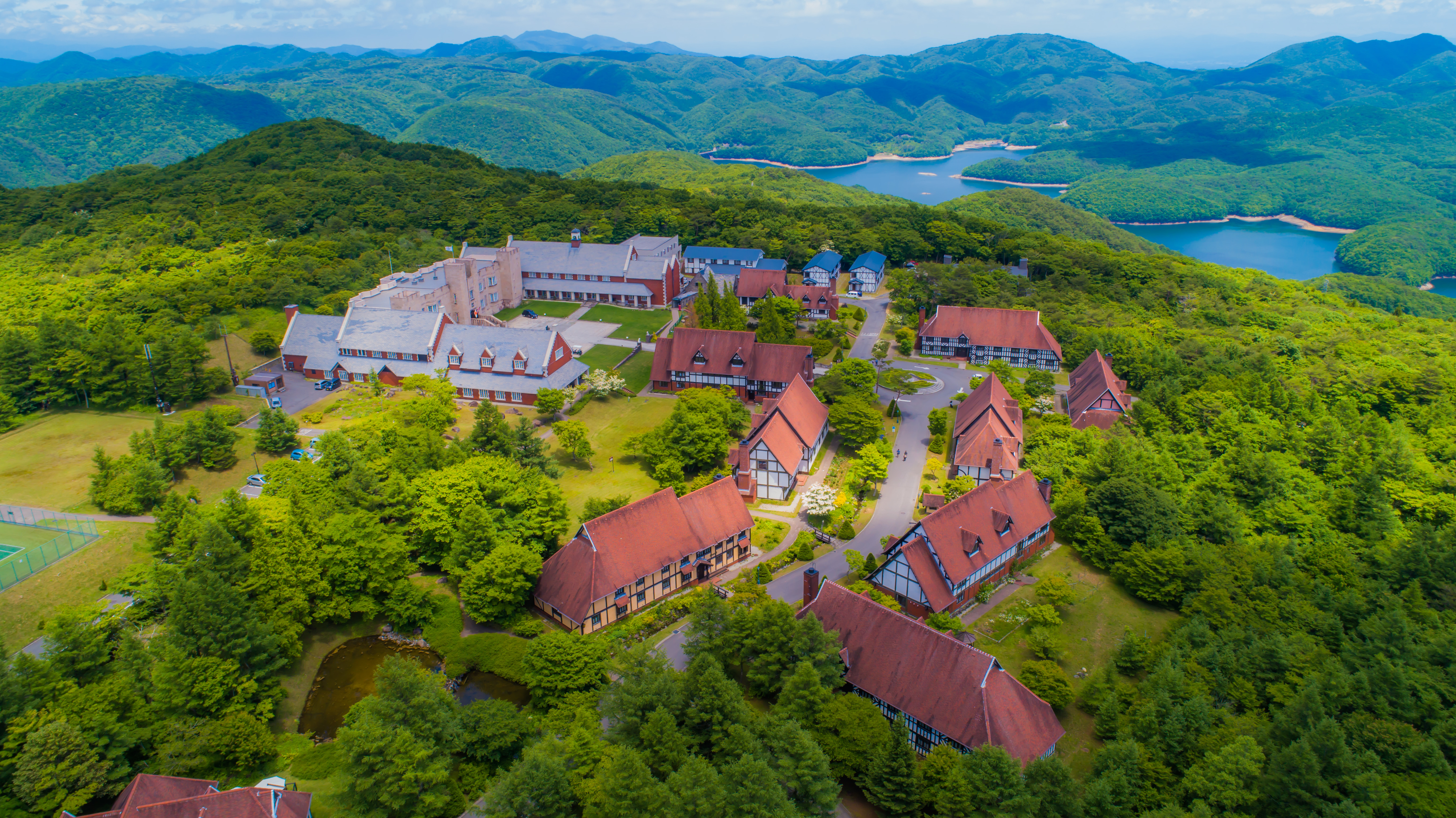 山々に囲まれた湖沿いのリゾート施設の上空からの写真です。