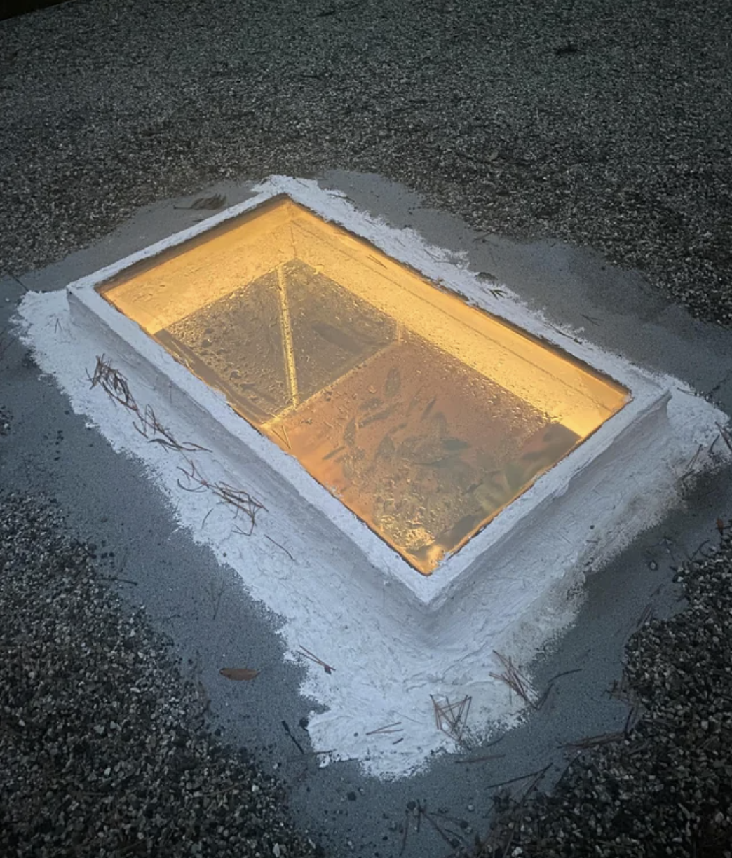 A lit-up empty pool at dusk with a house&#x27;s reflection