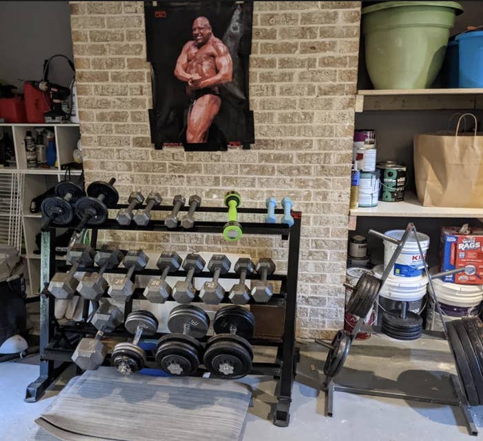 Individual sitting on a bench in a home gym with various weights and equipment around