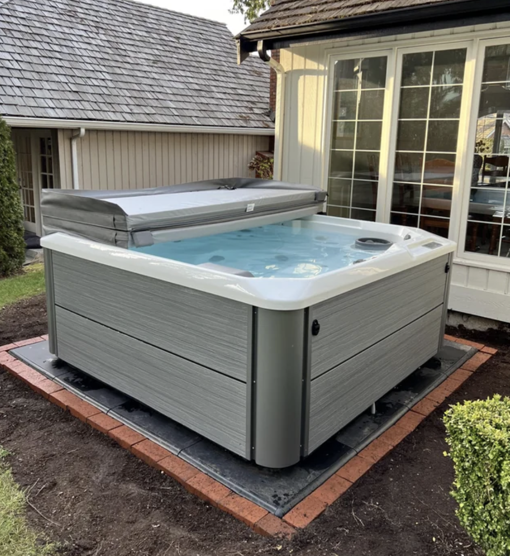 Hot tub installment on wooden deck outside a house, steps pending