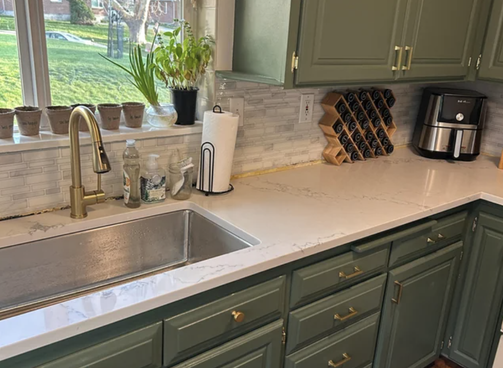 Renovated kitchen interiors with painted cabinets below green tape markings, uninstalled hardware, and a visible sink