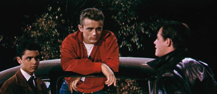 James Dean leans on a fence in &quot;Rebel Without a Cause,&quot; with two actors beside him