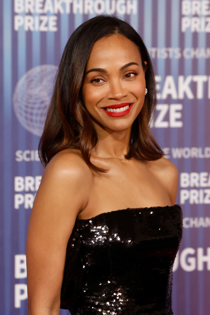 Zoe Saldana smiling in a black sequined dress at the Breakthrough Prize event